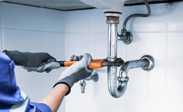 Technician providing kitchen sink plumbing services to address drainage issues and repairs